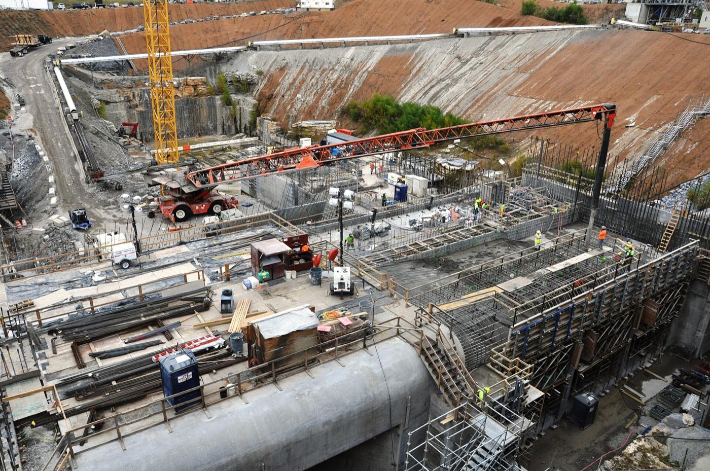 Aerial view of a navigation lock addition under construction: tower cranes, formwork, and rebar inside a rock cofferdam